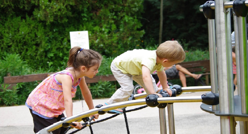 Two children climbing on playground equipment outdoors.
