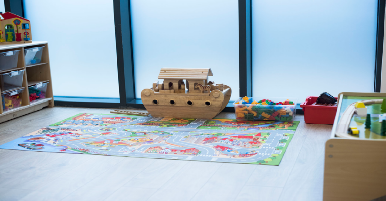 Colorful play area with a road map mat, wooden toy ark, and bins of building blocks.