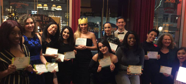 Group of people smiling and holding certificates during an indoor celebration event.
