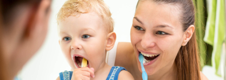 Woman and child brushing teeth together.