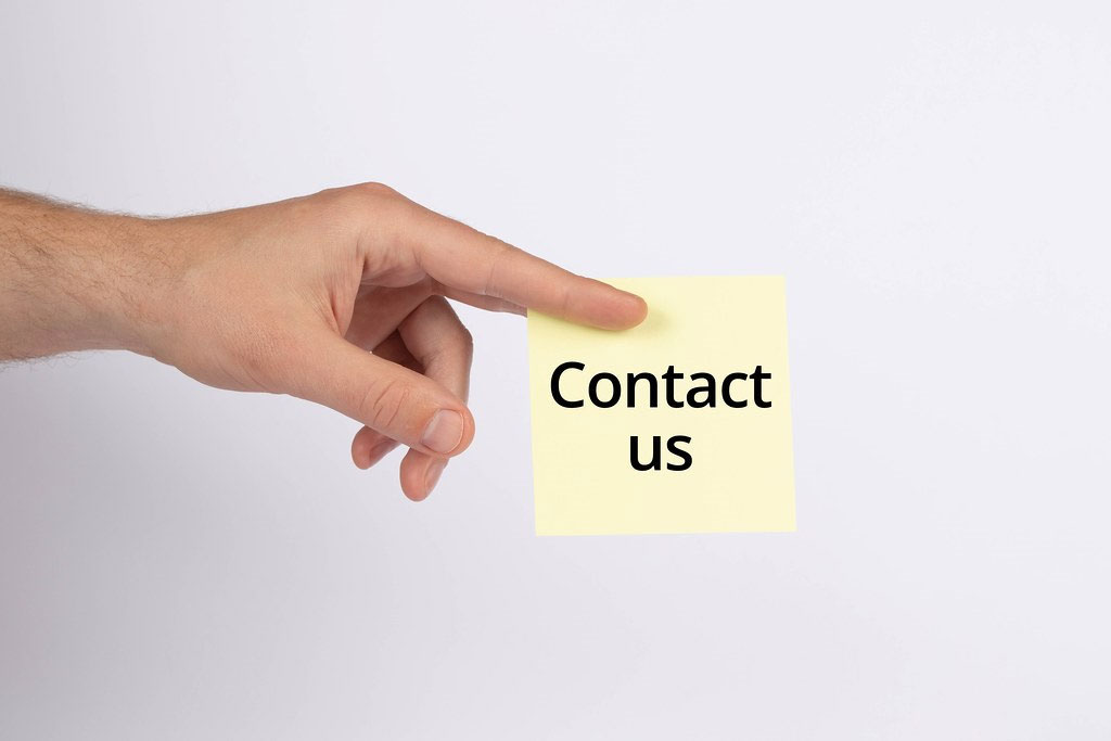 Hand holding a sticky note with “Contact us” text.