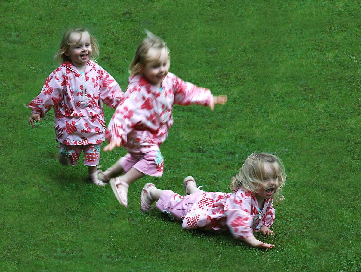Children running, stumbling, and falling on green grass.