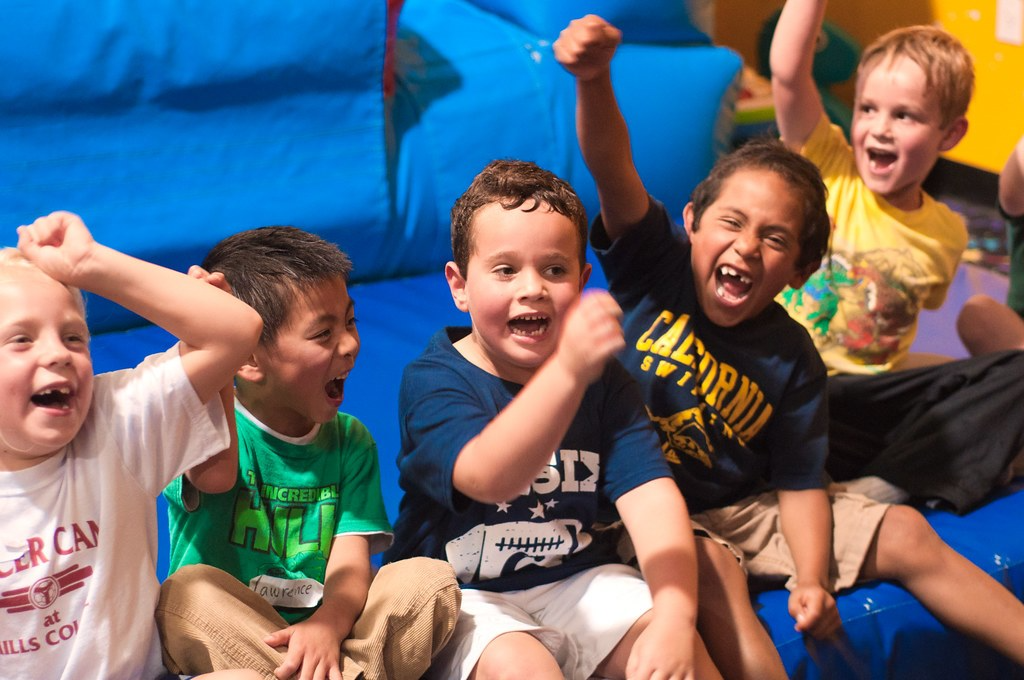 Group of excited children cheering together indoors.