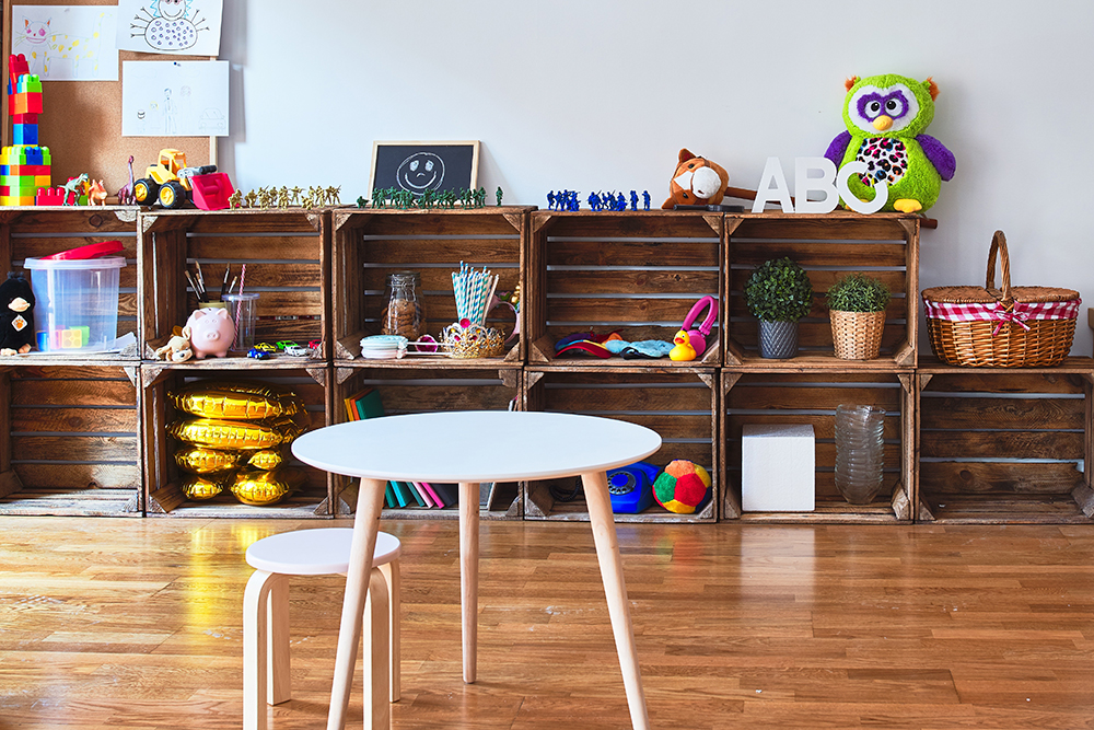 Wooden shelves filled with toys and art supplies in a play area.