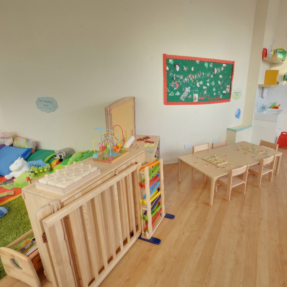 Playroom with wooden tables, chairs, and educational toys.